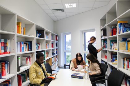 Junge Menschen in einer Schulbibliothek, welche sich mit medizinischer Literatur bzw. Lehrmaterial zur Pflege beschäftigen