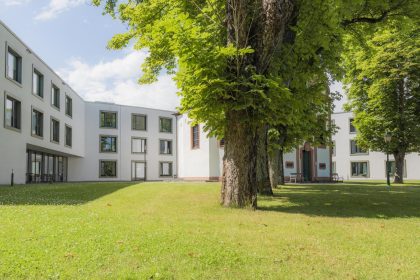 Rheinische Katholische Altenpflege, Gebäude mit Vorhof und Bäumen bei schönem Wetter, Außenansicht