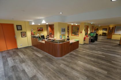 Der Empfangsbereich des Hermann-Josef-Altenheims ist weiträumig zu sehen. Eine Empfangsdame steht hinter der Empfangs-Theke.