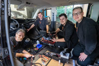 Ein Team von 4 Männern - Mechatroniker - arbeiten gut gelaunt im Inneren eines großräumigen Fahrzeugs